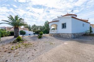 a white house with a palm tree in front of it at Villa Flor in Les tres Cales