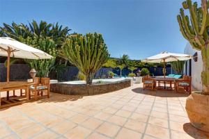 a patio with tables and chairs and umbrellas at Villa El Cactus in Teguise