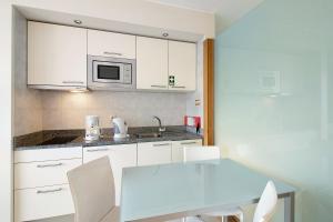 a kitchen with white cabinets and a table and a microwave at Dfm Happy Days C - Funchal in Funchal
