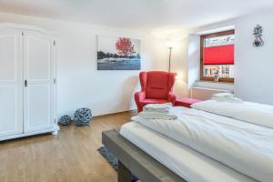 a bedroom with a red chair and a window at Haus Steinatal in Ühlingen-Birkendorf