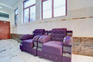 a purple couch sitting in a room with windows at Super Hotel O Raj Ghat Ayodhya Formerly Shree Siya Raman in Ayodhya