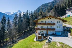 a house on a hill with mountains in the background at Ferienwohnung Helena in Schwendau