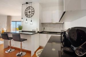 a kitchen with a counter and a clock on the wall at Apartamento Lolita com Terraço in Caniço