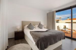 a white bedroom with a bed and a balcony at Apartamento Lolita com Terraço in Caniço