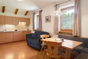 a kitchen and living room with a table and a blue chair at Stinerhof Panoramablick in Vols am Schlern