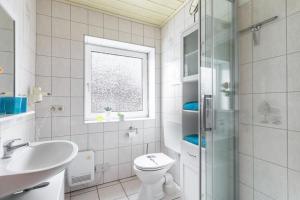 a white bathroom with a toilet and a sink at Ferienhaus Kikki in Friedrichskoog-Spitze