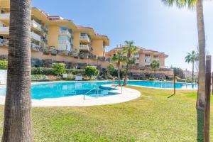 a view of a resort with a swimming pool and palm trees at Lovely Apartment Higueron in Benalmádena