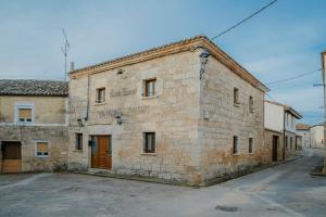an old stone building with a brown door on a street at El Humilladero in Sasamón