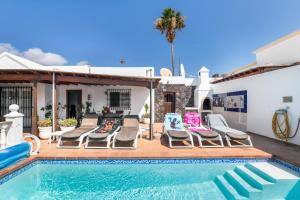 a swimming pool with chaise lounge chairs next to a house at Casa Colleen in Puerto del Carmen