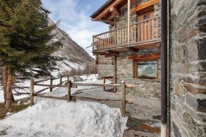 a log cabin with a wooden balcony and snow at La Maison du Brenand in Rhêmes-Notre-Dame