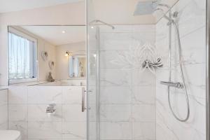 a white bathroom with a shower with a glass door at Feriendomizil Bergamini in Bischoffingen +28 photos