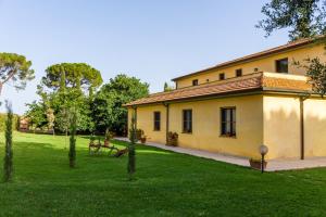a yellow house with a grass field and trees at Capracotta - Alba in Montemassi