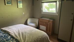 a bedroom with a bed and a chair and a window at Peniche l’Arlésienne in Arles