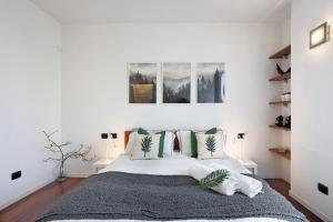 a white bedroom with a large bed with green pillows at vb home brianza in Costa Masnaga