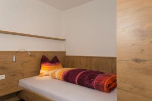 a bed with a multicolored pillow on top of it at Alpenblick Nr 6 in Campo Tures