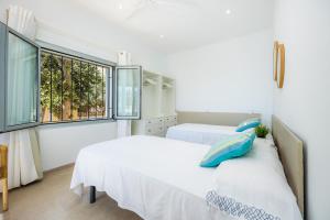 two beds in a white room with a window at Casa Antonia in Cala Millor