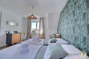 a bedroom with two beds and a large wall at Le passé composé in Ploubazlanec