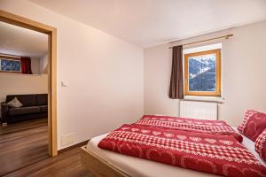 a bedroom with a red bed and a window at Golserhof Kristall in Cadipietra