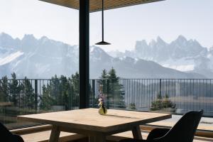 a wooden table in front of a large window with mountains at anders mountain suites 1 in Brixen