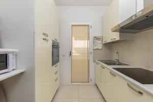 a white kitchen with a sink and a microwave at Residenza Cormorani 2 in Golfo Aranci
