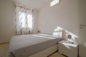 a white bedroom with a bed and a window at Villa Terry in Ostuni
