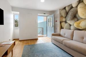 a living room with a couch and a large rock wall at Casa do Calhau in Câmara de Lobos