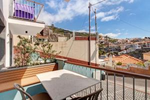 a balcony with a table and a view of a city at Casa do Calhau in Câmara de Lobos