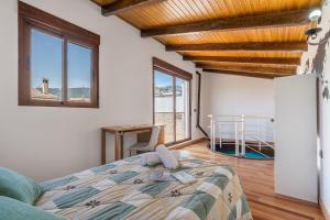 a bedroom with a bed and a desk and windows at Casa Petra in Illora