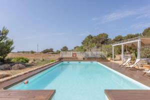 a large swimming pool with a deck and a house at Can Juan Pedro in La Mola