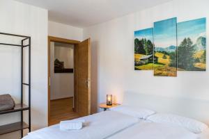 a bedroom with a white bed and paintings on the wall at Apartment Luisa in Scharnitz