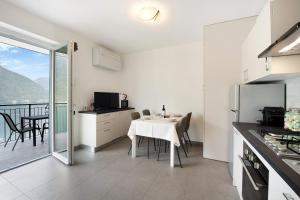 a white kitchen with a table and a balcony at Appartamento 4 in Nesso