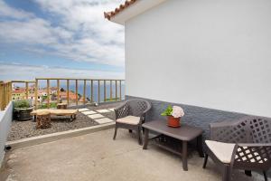 a balcony with chairs and a table on a building at Casa da Ribeira da Janela in Porto Moniz