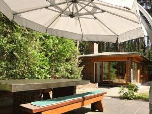 a picnic table with an umbrella and a bench at Waldhaus Jakober in Maasdorf