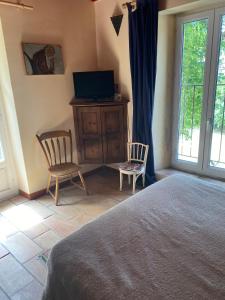 a bedroom with a bed and two chairs and a television at Buvolaccia in Sampolo +4 photos
