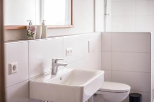 a white bathroom with a sink and a toilet at Ferienwohnung Häfele 1 in Bad Wurzach +18 photos