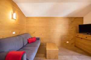 a living room with a blue couch and a television at Rosalpina Apt 2 in San Vigilio Di Marebbe