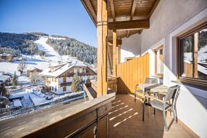 a balcony with a table and chairs and a snow covered mountain at Rosalpina Apt 2 in San Vigilio Di Marebbe