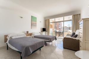 a bedroom with two beds and a couch at Sunny studio with seaview in Fuengirola