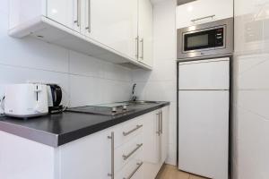 a white kitchen with a sink and a microwave at Sunny studio with seaview in Fuengirola +10 photos