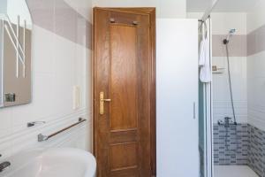 a bathroom with a wooden door and a sink at Las Alondras in Gandía +14 photos