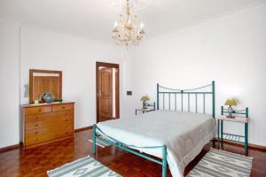 a bedroom with a bed and a dresser and a chandelier at Casa Imaginário Com Serenidade in Caldas da Rainha