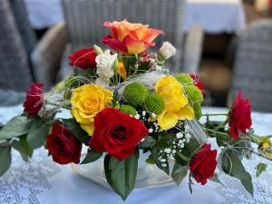 a vase filled with red and yellow flowers on a table at Ferienhof Renate Sassen in Werdum