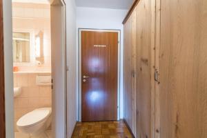 a bathroom with a toilet and a wooden door at Ferienwohnung Förchensee in Ruhpolding +21 photos