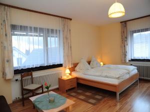 a bedroom with a bed and two windows and a table at Kuryhof in Simonswald