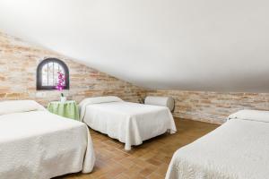 a room with three beds and a brick wall at Chalet Aragon Muñoz in Conil de la Frontera +17 photos