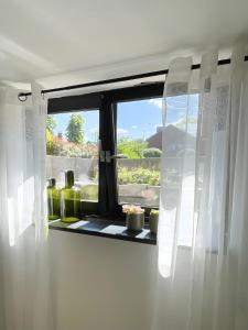 a window with white curtains and bottles on a window sill at Ruhiges Apartment Münster Baumberge in Nottuln
