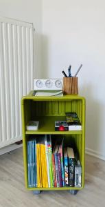 a green book shelf filled with books next to a radiator at Ruhiges Apartment Münster Baumberge in Nottuln