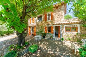a stone house with a table and a tree at Gîte Chez Martha in Anduze