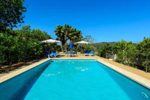 a swimming pool with blue chairs and umbrellas at Villa Can Joan den Coves in Santa Gertrudis de Fruitera