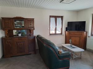 a living room with a leather couch and a tv at Maison Maurer in Aschbach